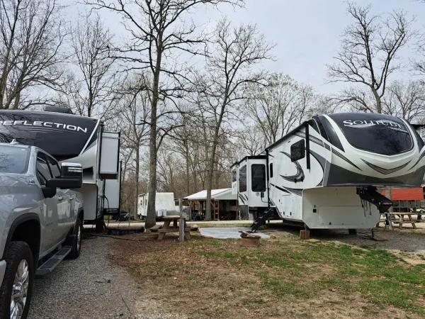 Two large, modern fifth-wheel trailers, a Grand Design Reflection and a Grand Design Solitude, parked at neighboring campsites at Kountry Resort Campground.