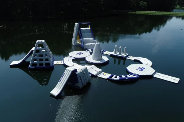 High-angle aerial drone shot of the entire floating inflatable Aqua Park layout on the calm lake at Kountry Resort Campground.