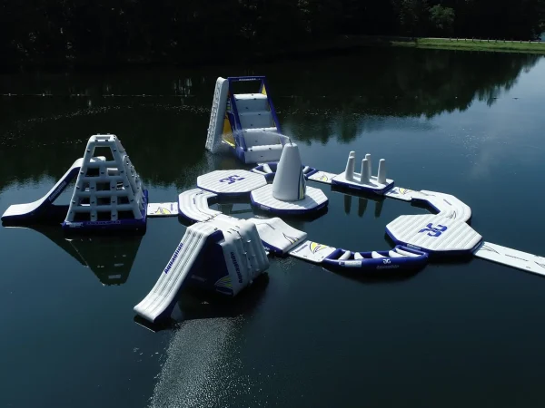High-angle aerial drone shot of the entire floating inflatable Aqua Park layout on the calm lake at Kountry Resort Campground.