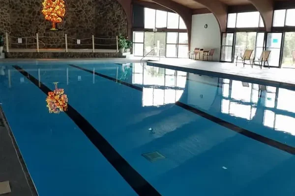 A large, pristine indoor swimming pool under a vaulted wooden ceiling with exposed beams at Kountry Resort Campground.