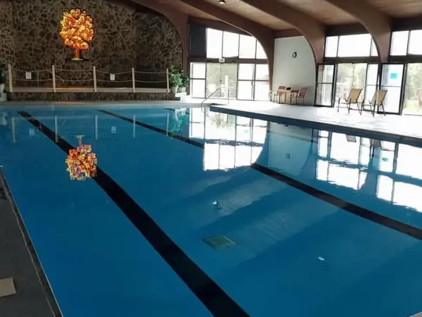 A large, pristine indoor swimming pool under a vaulted wooden ceiling with exposed beams at Kountry Resort Campground.