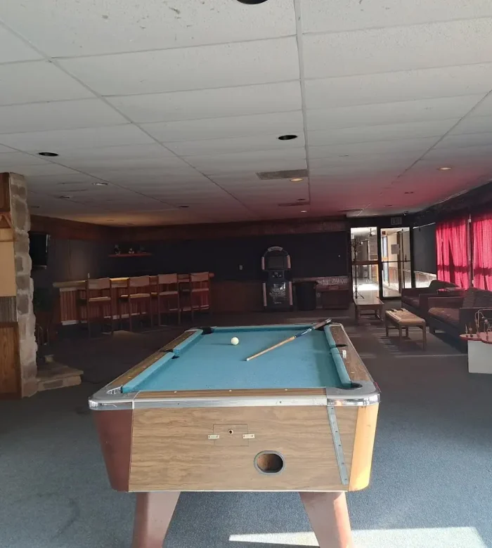 Indoor recreation center and game room at Kountry Resort Campground featuring a central pool table, arcade machines, and a bar counter.